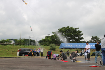 曇り空で天気が悪い中、ペットボトルロケットを飛ばしている写真