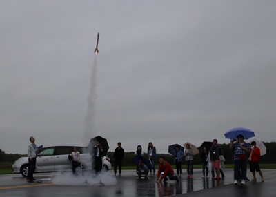 製作したモデルロケットの打ち上げを見守る高校生参加者たちの写真