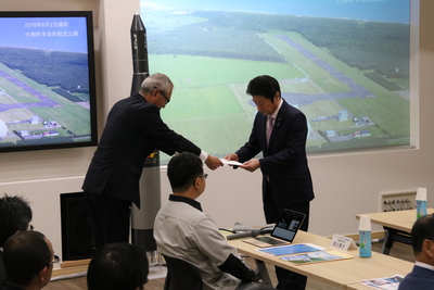 SORAの集会室にて、酒森町長より要望書を受け取る松山内閣府特命担当大臣の写真