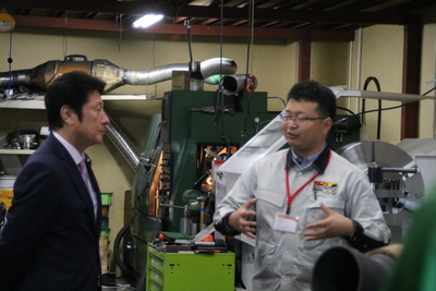 大型機器群の前で稲川社長からの意見を聞く松山内閣府特命担当大臣の写真