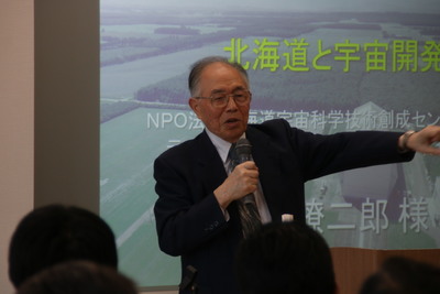 マイクを片手に講演を行う秋葉名誉教授の写真