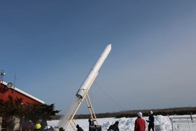 雪原の中、大空へ向けて勢いよく打ち上がる巨大ペットボトルロケットの写真