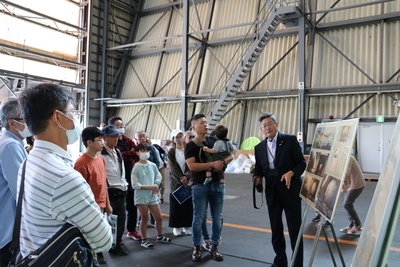 北海道スペースポート見学ツアーにて格納庫内で町長からパネルでの解説を受けている様子の写真