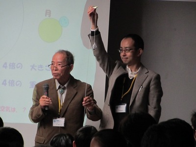 実験道具を手にしつつ講演を行う、平林教授等講師2名の写真