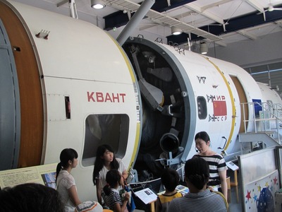 苫小牧市科学センターのミール展示館にて、宇宙ステーション「ミール」の実物予備機を見学する旅行団一行の写真